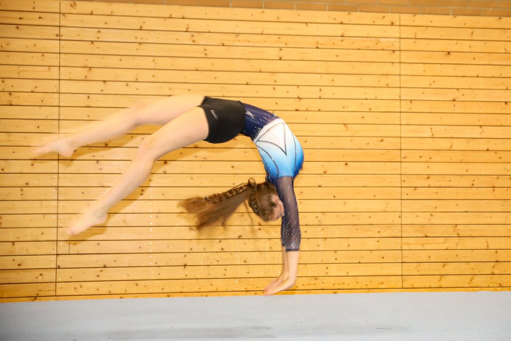 Bild von der Seite. Eine Turnerin springt einen Menichelli.