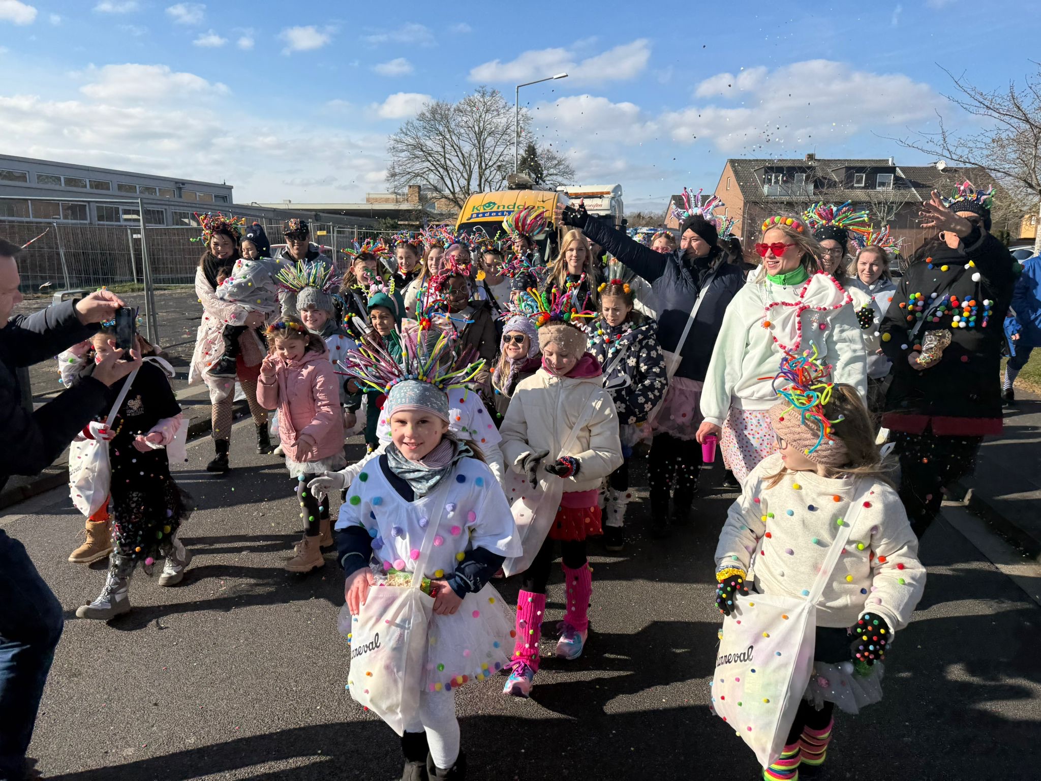 Gruppenfoto: Viele Teilnehmenden in bunten Konfetti-Kostümen während des Karnevalszugs..