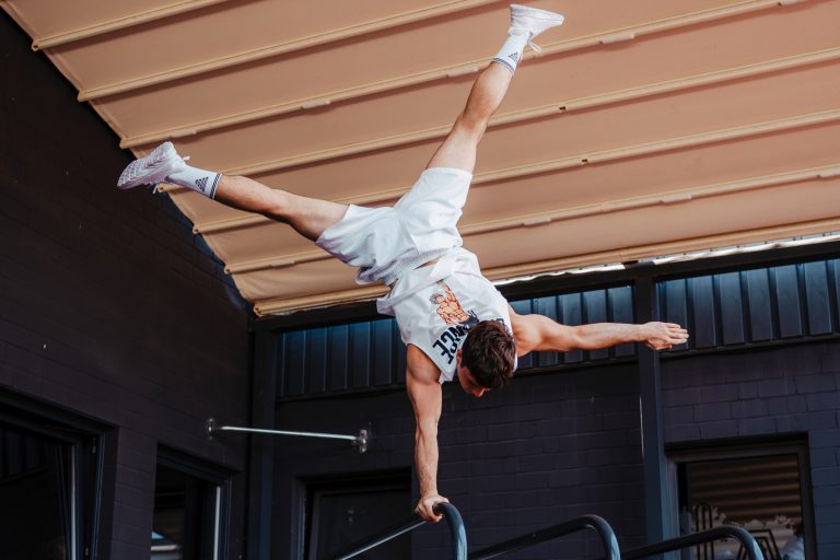 Mann von hinten bei einer Calisthenics-Übung am Parallelbarren.