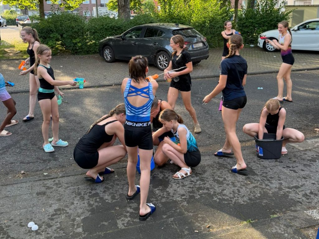Viele Mädels in Sporttrikots bei einer wilden Wasserschlacht auf unserem Parkplatz.